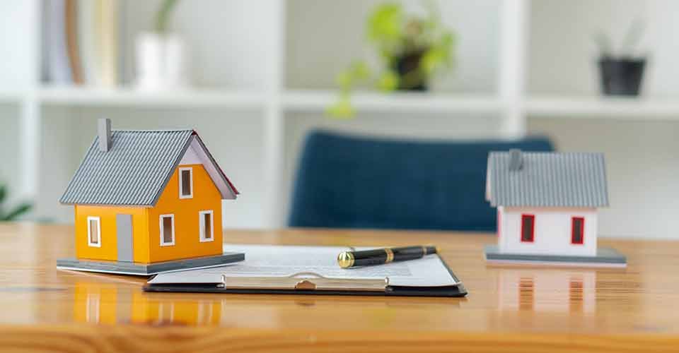 Model homes and a purchase contract on table with pen