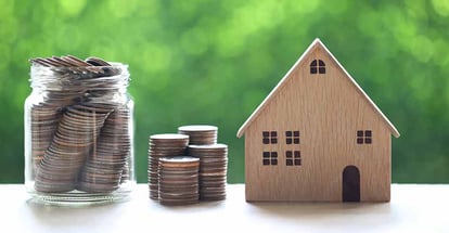 Model house and coins in glass bottle