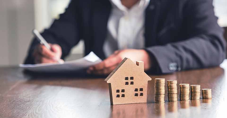 Model house and coins placed on wooden table