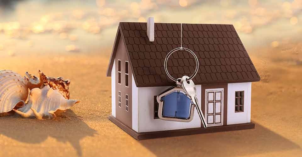 Model house and key on sandy beach