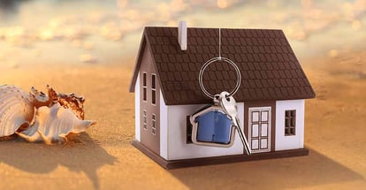 Model house and key on sandy beach
