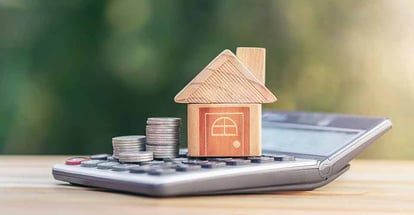 Model house and stack of coins is placed on the calculator