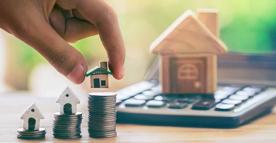 Model house on coins stack and calculator