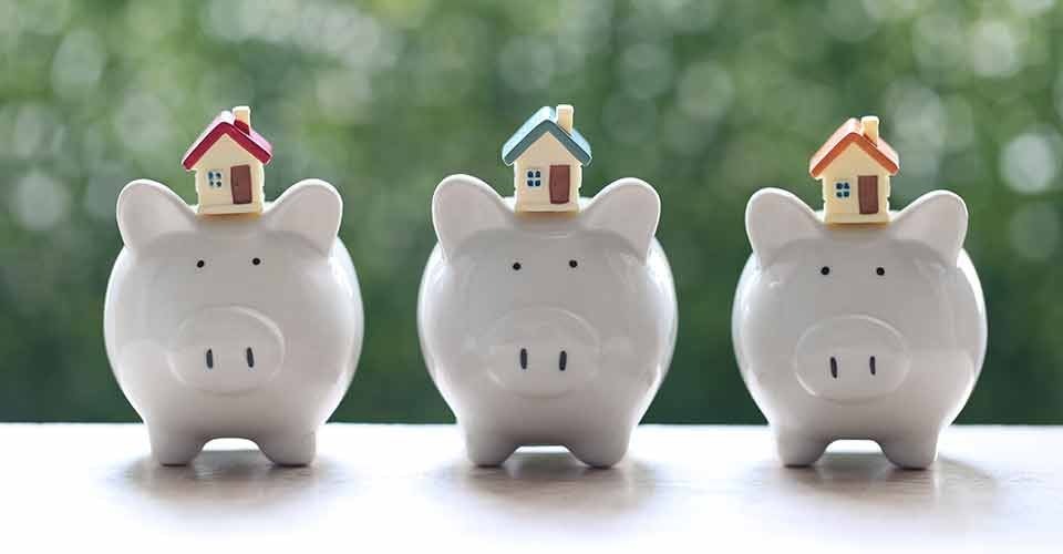 Model house on piggy bank with stack of coins