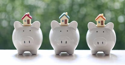 Model house on piggy bank with stack of coins