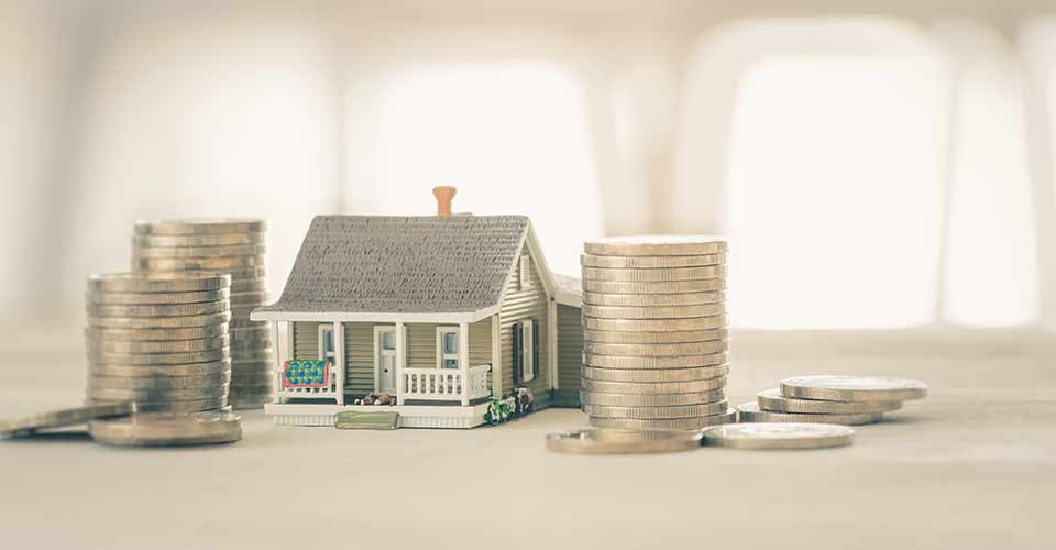 Model house on white wooden floor with stack coin depicting residential asset to live and invest for own benefit