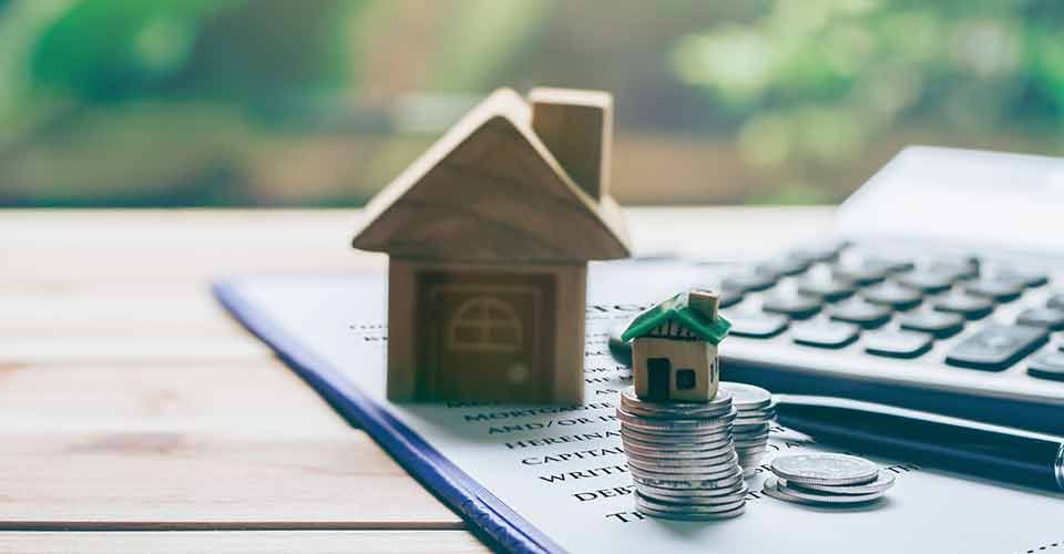 Model house placed on coins and notebook