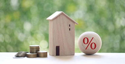 Model house with percentage symbol and stack of coins