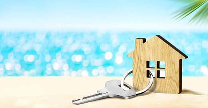 Model of house and key on sandy beach