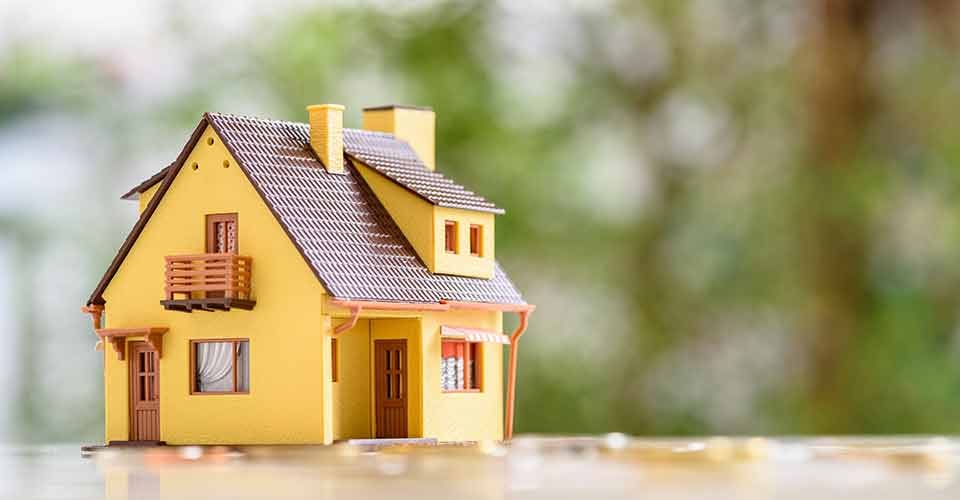 Model residential house and coins on a table