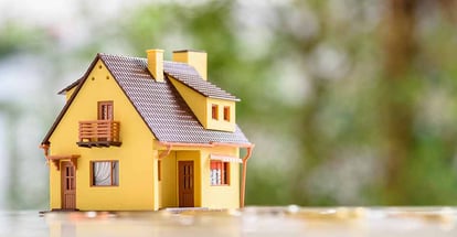 Model residential house and coins on a table