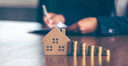 Model wooden houses with stack of coins placed on wooden tables