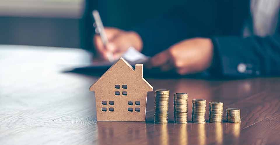 Model wooden houses with stack of coins placed on wooden tables