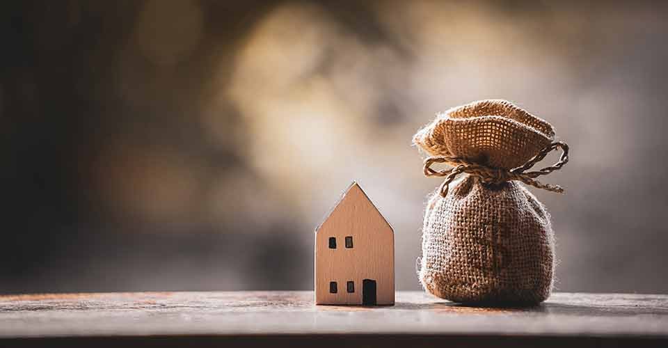 Money bag and home model on the wooden table