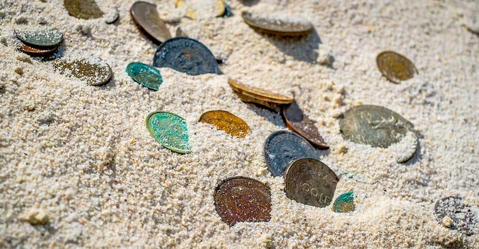 Old coins partially buried in white sand
