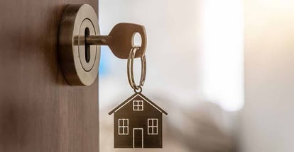 Open door to a new home with key and home shaped keychain