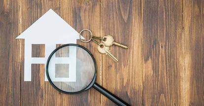 Paper house and key with magnifying glass for house hunting