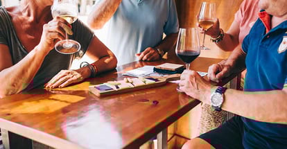 People eat cheese and drink wine in a restaurant on a terrace on a sunny day