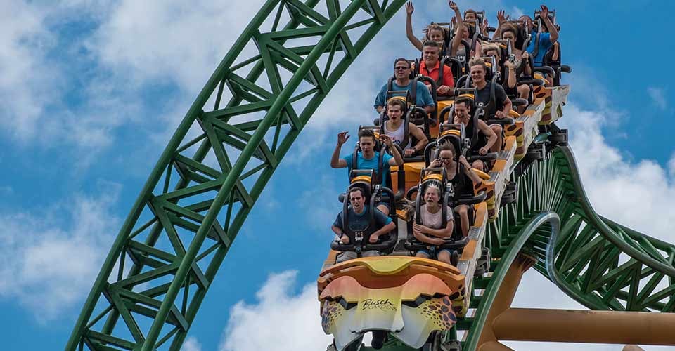 People enjoying Cheetah Hunt rollercoaster on lightblue cloudy sky in Tampa Bay Florida