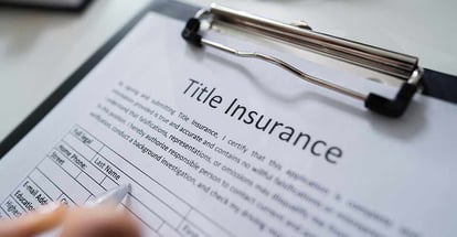 Person Filling Title Insurance Form Over White Desk