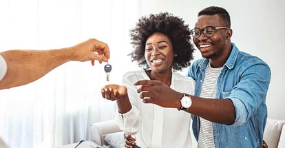 Photo of a smiling young couple thanking to the agent for the new house