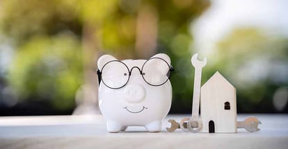 Piggy bank and home model with construction tools for renovation