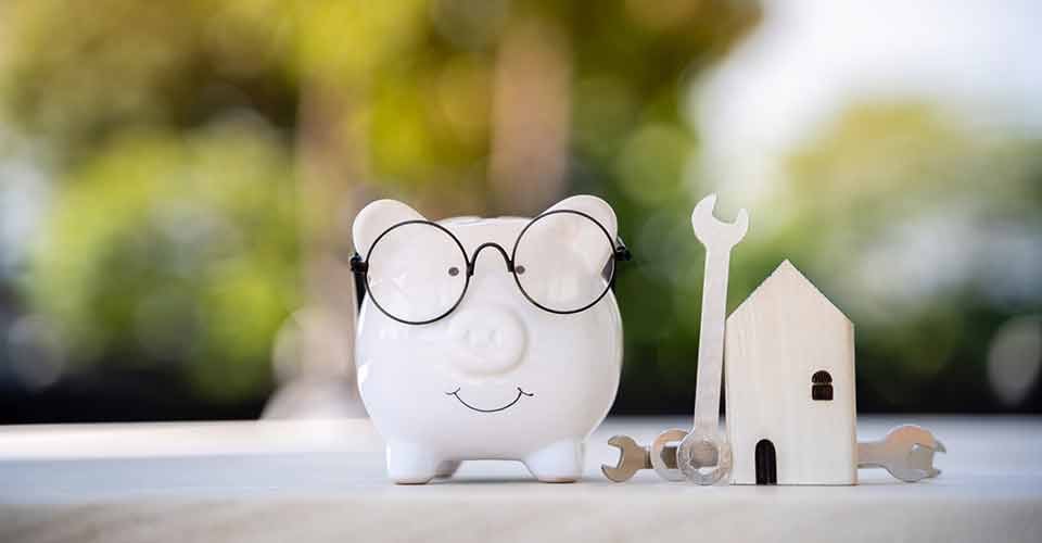 Piggy bank and home model with construction tools for renovation