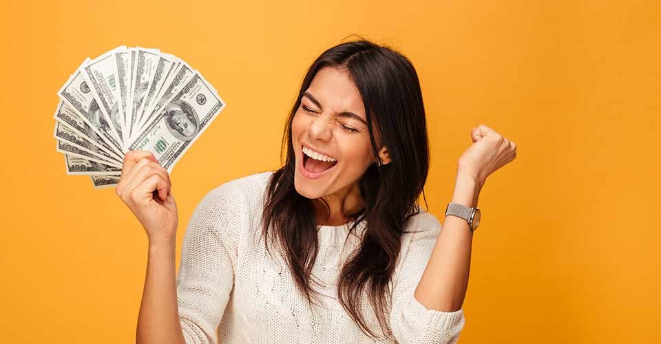 Portrait of a cheerful young woman holding money banknotes and celebrating
