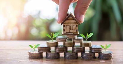 Putting house model on coins stack for property investment
