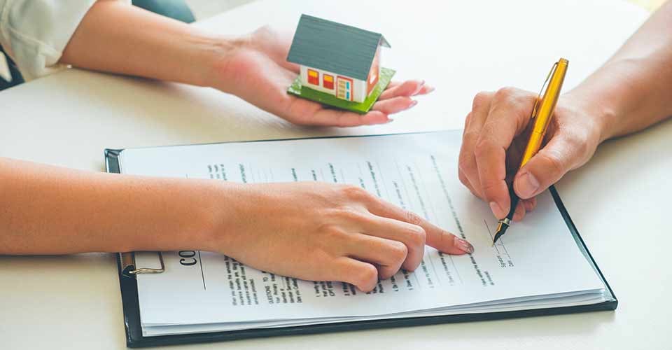 Real Estate Agent showing where to sign on document for buy house contract