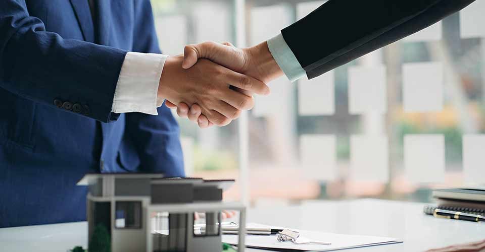 Real estate agent and client shaking hand after discussing home purchases