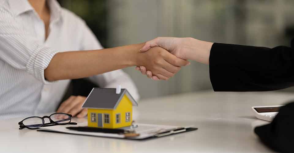 Real estate agent and customer shaking hands after signing a home purchase contract