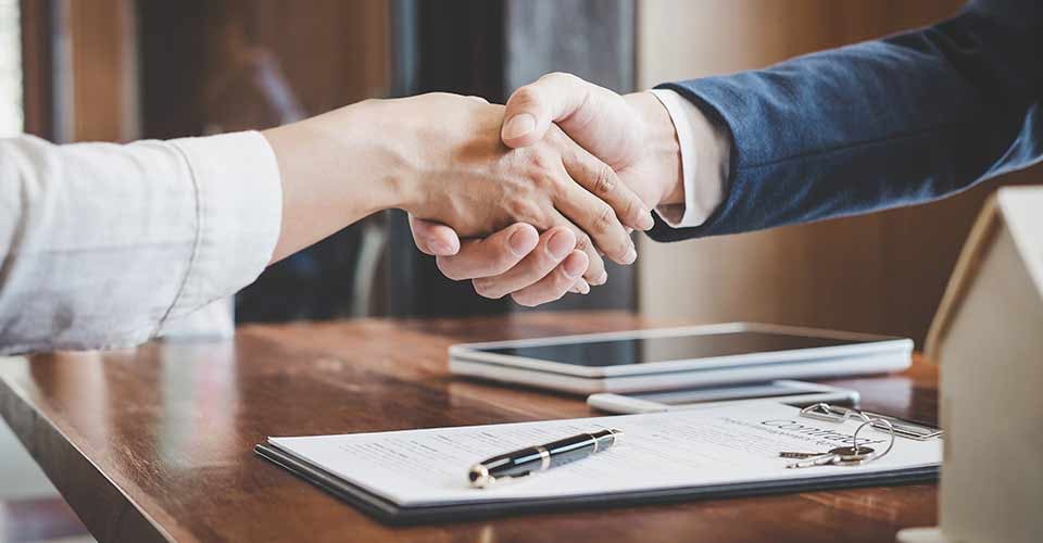 Real estate agent and customers shaking hands together after signing contract