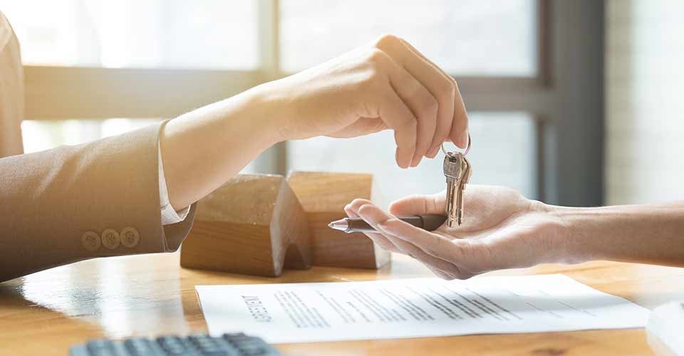 Real estate agent giving house keys to buyer after signing purchase agreement