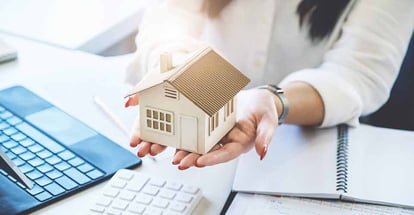 Real estate agent handing model house to buyer along with documents to sign