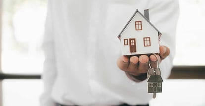 Real estate agent holding a model residential house and keys on hand