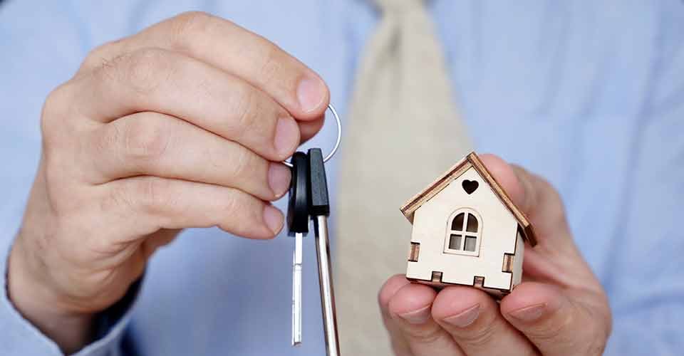 Real estate agent holding house keys and wooden house model