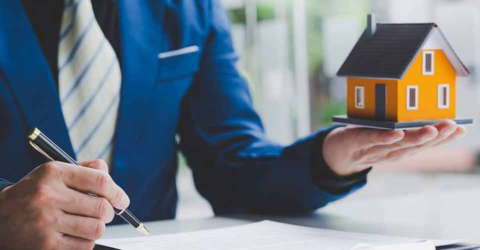Real estate agent pointing to the house model and explains home purchase contract