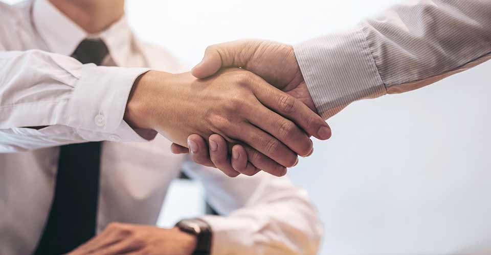 Real estate broker agent and customer shaking hands after signing contract documents