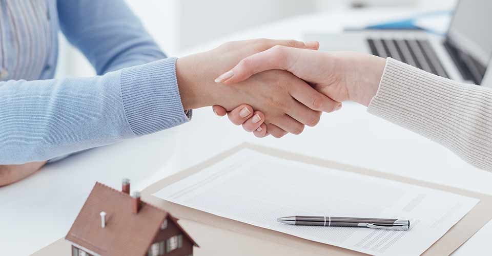 Real estate broker and customer shaking hands after signing a contract