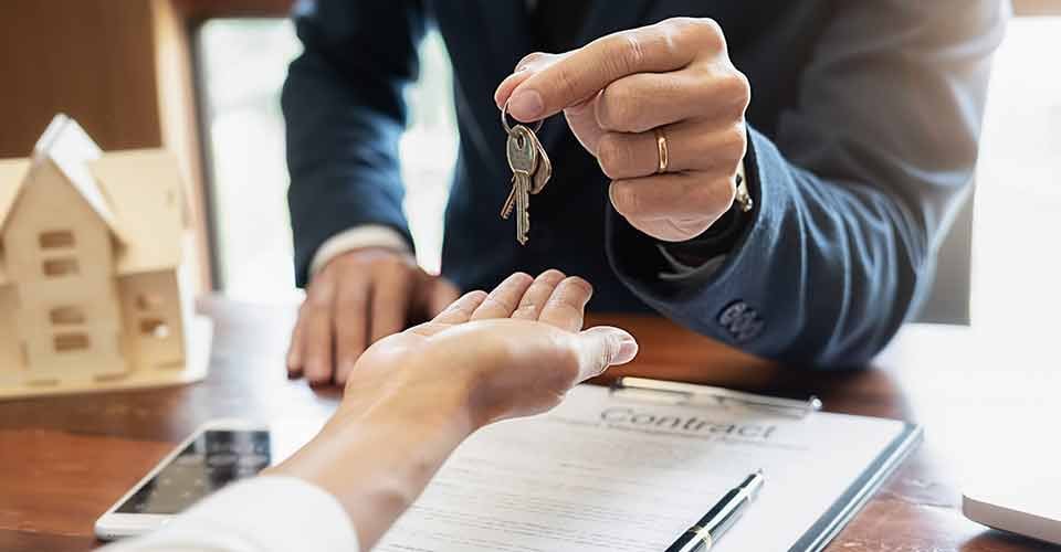 Real estate broker give new house key to buyer after signing contract