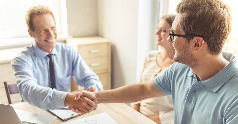 Realtor shaking hands with buyer after signing house purchase contract