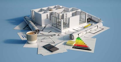 Residential unit model on top of a table with home renovation blueprints