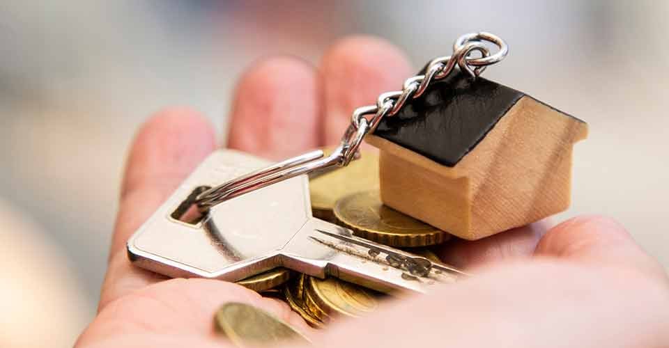 Retiree hand holding house keys and coins