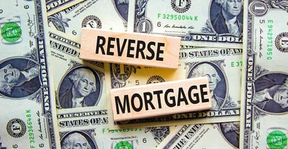 Reverse mortgage words on wooden blocks with dollar bills background