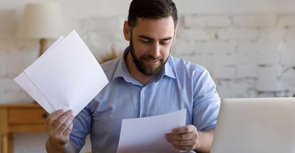Satisfied man doing paperwork and reading financial documents