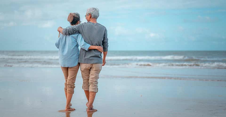 Senior couples walking on the beach at sunny day