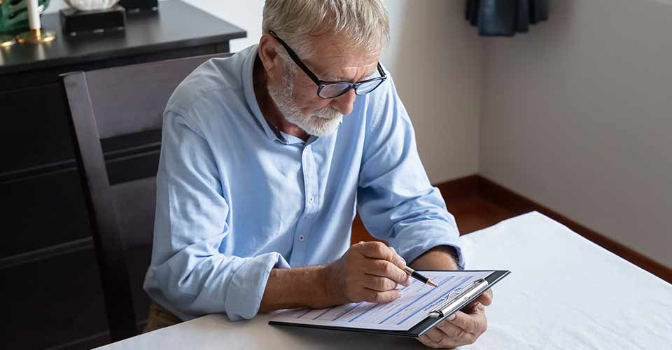 Senior old man reading and examining mortgage application form