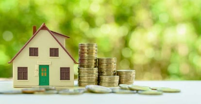 Small house model with green door and stacks of rising coins