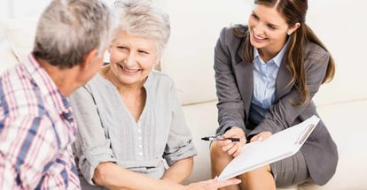 Smiling businesswoman showing documents to senior couple in living room